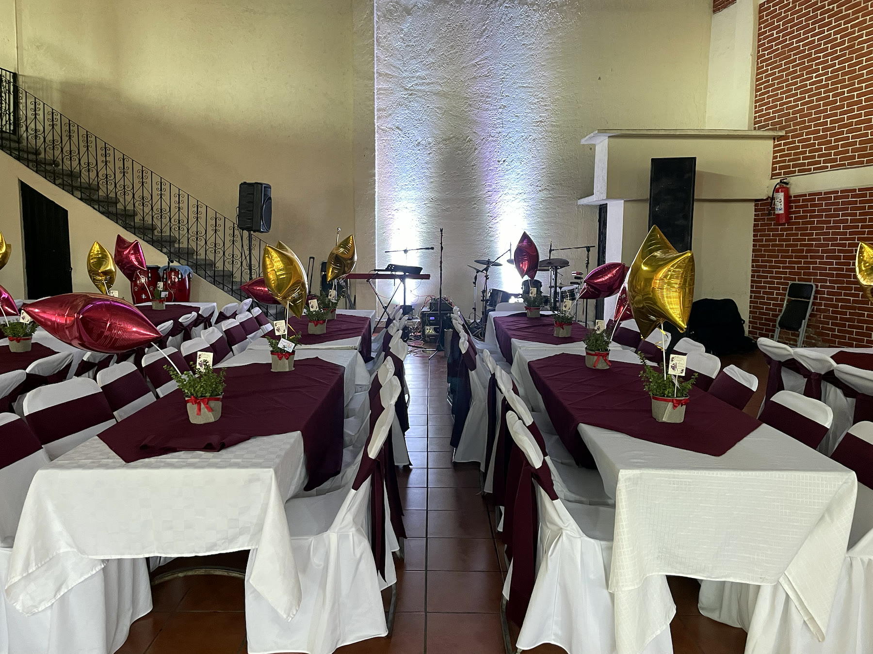 Mesas preparadas con mantelería vino y blanca